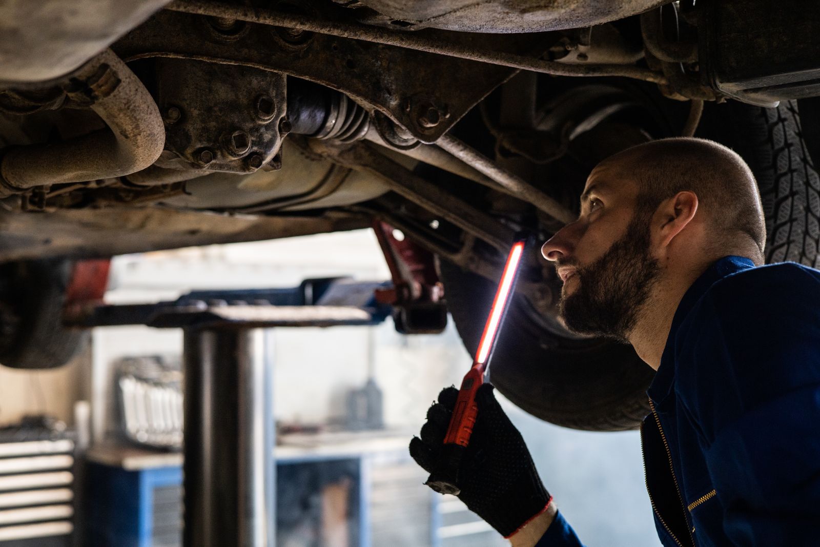 A mechanic inspecting the underside of a car on a lift